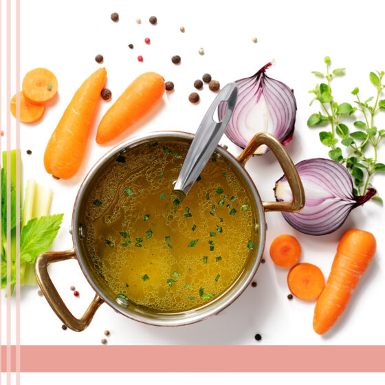 A saucepan with vegetables around with bone broth in the pan.